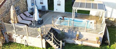 Un jardin avec une piscine, un espace salon couvert et un mur en pierre.