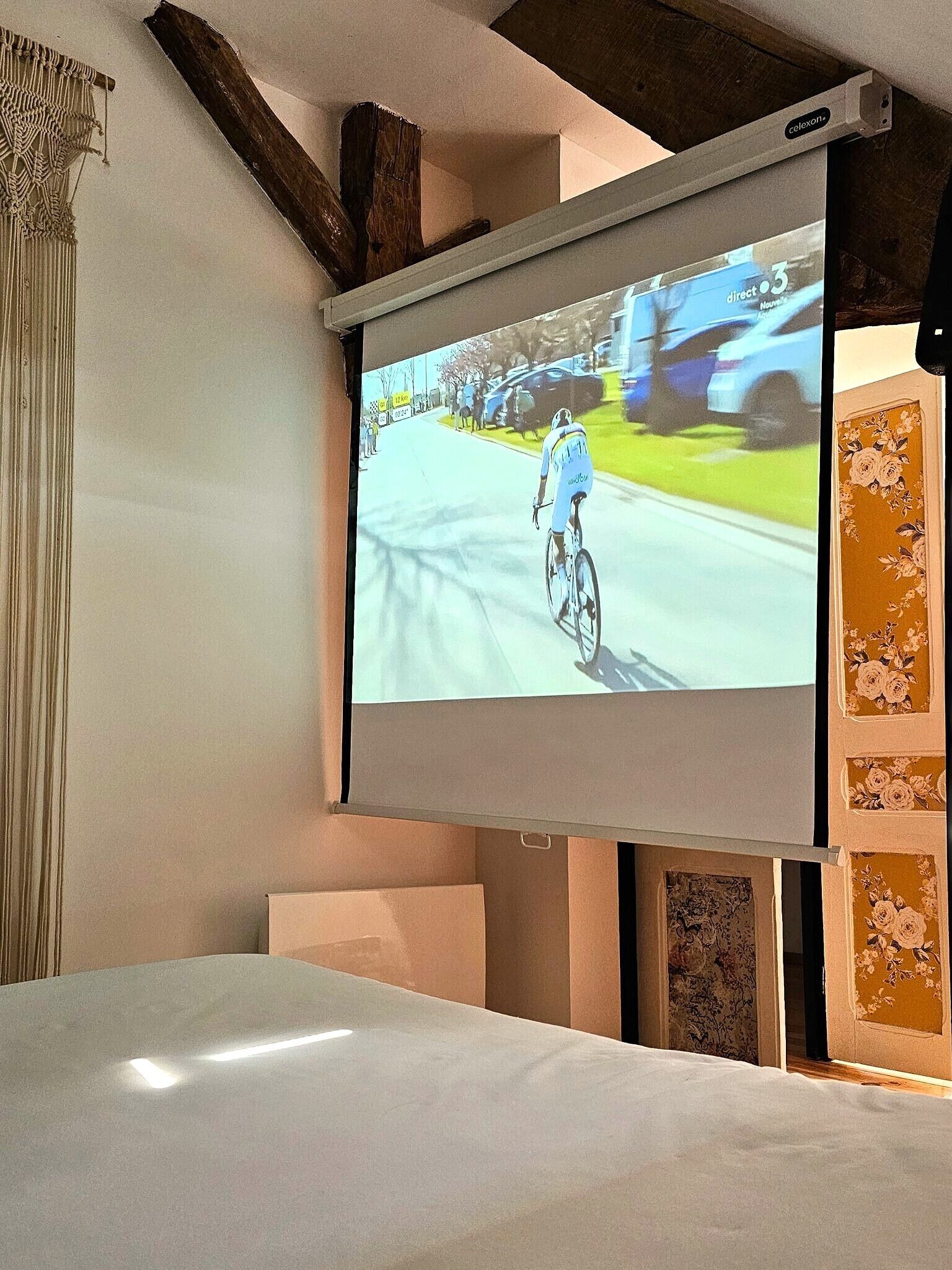 Un téléviseur fixé au mur diffuse un événement cycliste.