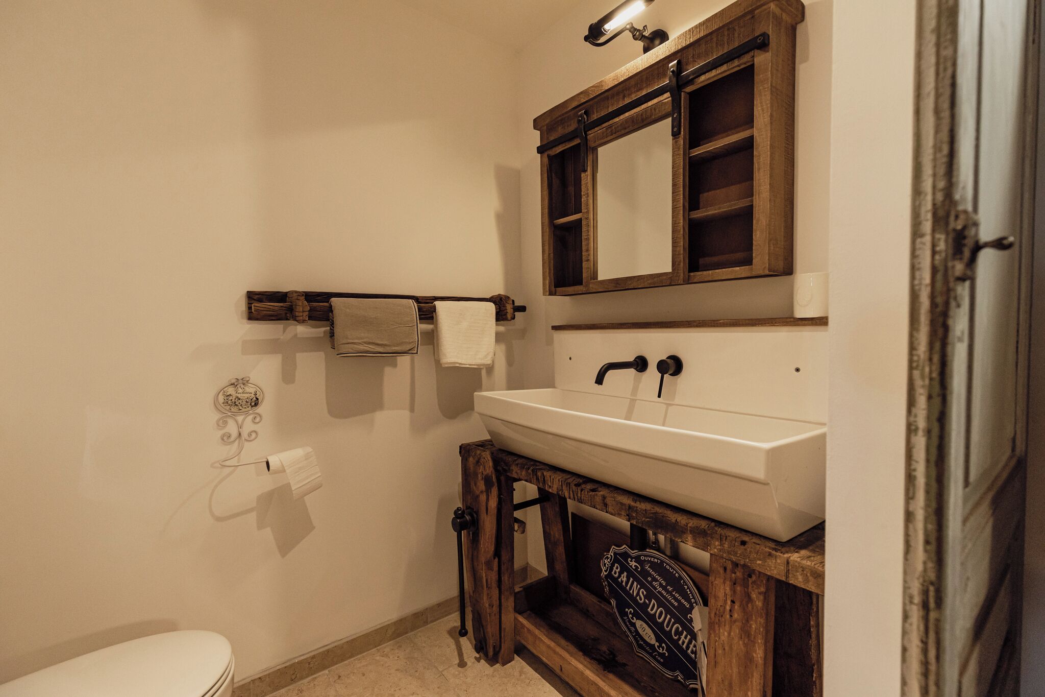 A bathroom with a white sink, wooden vanity, and a mirror above the sink.
