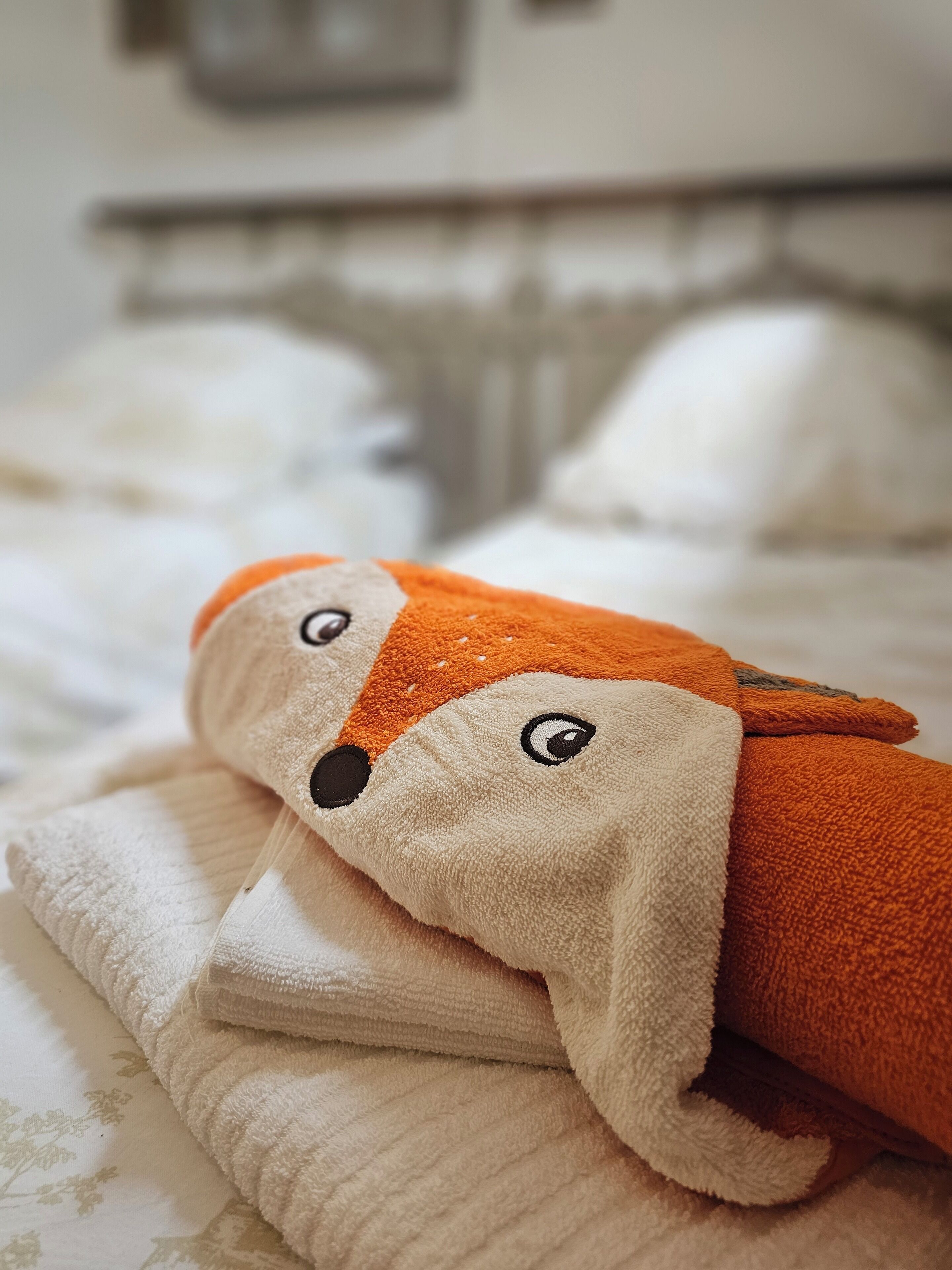 A bed with a white comforter and a folded blanket.
