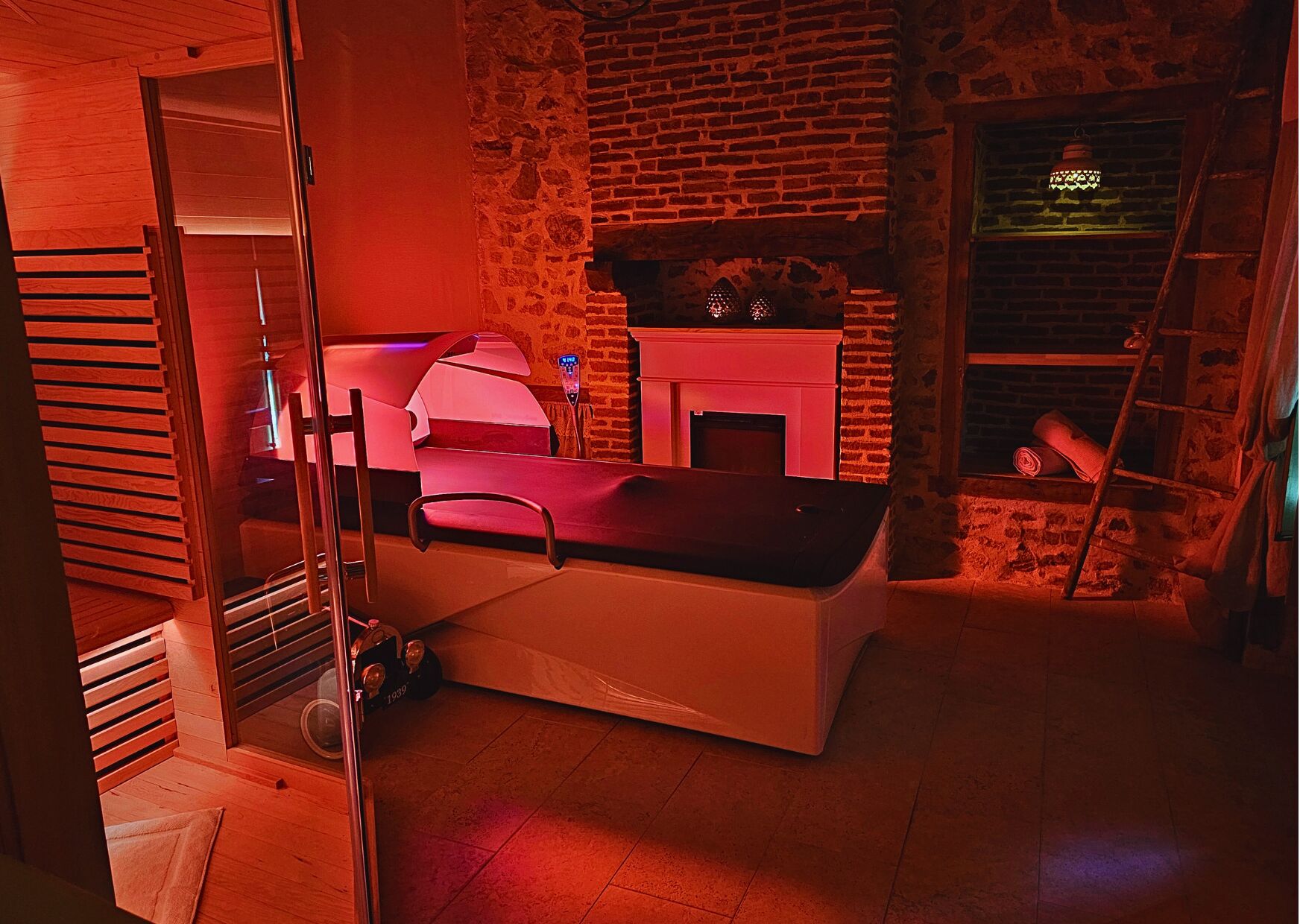 A room with a massage table, a brick fireplace, and a ladder leaning against the wall.