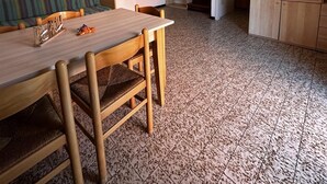 Un espacio habitable compacto con una mesa de comedor, sillas, un sofá, una escalera y un armario con puertas de vidrio.