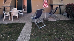 Un edificio de dos plantas con un balcón, asientos al aire libre y una bandera estadounidense.