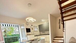 Un apartamento moderno con comedor, cocina y escalera.