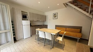 Una cocina compacta con una mesa de comedor y sillas, un sofá y una escalera.