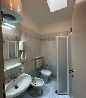 A bathroom with a sink, two toilets, a shower, and a mirror.