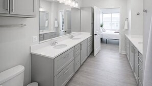 Un bagno moderno con lavabo doppio, uno specchio grande e una doccia a ingresso libero.