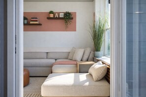 A modern living room with a sectional sofa, a coffee table, and a bookshelf with decorative items.