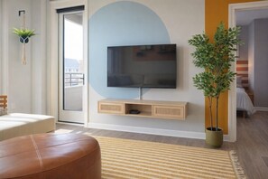 Una sala moderna con una televisión de pantalla plana, un sofá, una mesa de centro, una planta en maceta y una puerta corredera que da a otra habitación.