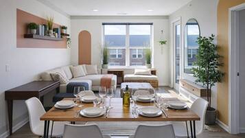 Comedor con mesa de madera dispuesta para cuatro personas, rodeado de sillas blancas.