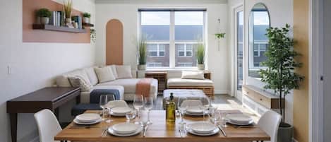 Comedor con mesa de madera dispuesta para cuatro personas, rodeado de sillas blancas.