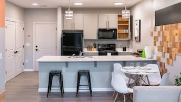 Una cocina moderna con una isla central, taburetes de bar y un comedor con mesa y sillas.