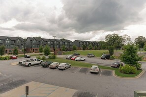 A parking lot with multiple cars and a row of apartment buildings in the background.