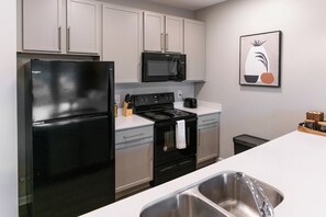A modern kitchen with a black refrigerator, stainless steel sink, and a microwave.