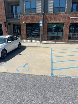 A parking lot with a white car parked in a handicapped space.