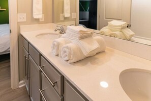 A bathroom with a sink, mirror, and a stack of folded towels.