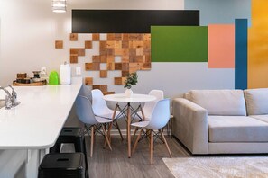 Een moderne keuken met een wit aanrecht, een spoelbak en een eethoek met een ronde tafel en stoelen.