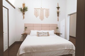 A bedroom with a bed, bedside tables, and wall decorations. - Cozy Mill Loft w/ 2 king beds, huge windows (Spartanburg)