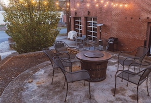 An outdoor patio with a round table and chairs, a barbecue grill, and string lights. - Cozy Mill Loft w/ 2 king beds, huge windows (Spartanburg)