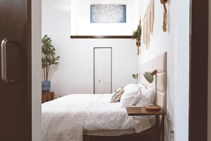 A bedroom with a bed, bedside table, lamp, and a door. - Cozy Mill Loft w/ 2 king beds, huge windows (Spartanburg)