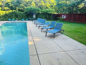 A swimming pool with lounge chairs and a wooden fence in the background. - Cozy Mill Loft w/ 2 king beds, huge windows (Spartanburg)