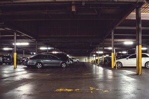 Un estacionamiento subterráneo de varios niveles con automóviles estacionados en filas, iluminado por luces superiores.