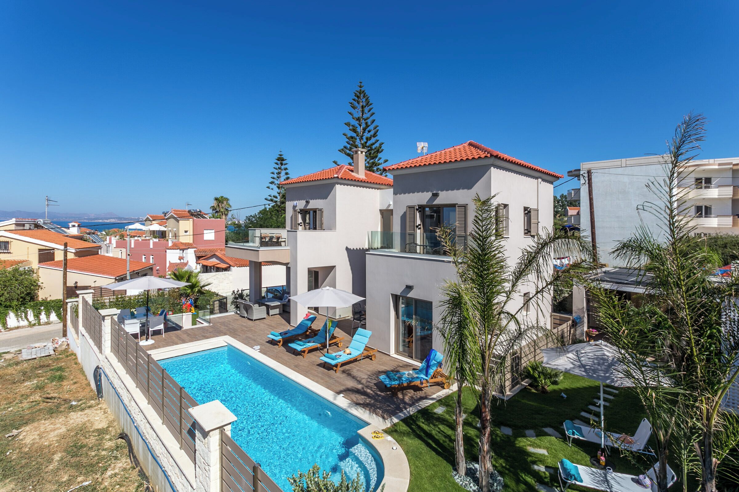 Ein modernes Resort mit Swimmingpool, Liegestühlen und Blick aufs Meer.