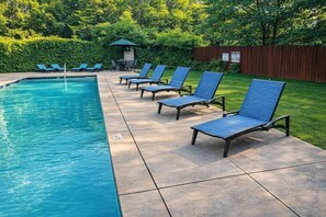 A swimming pool with lounge chairs and a wooden fence.