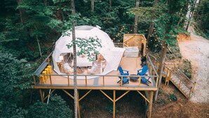 Una casa en árbol con estructura tipo cúpula, terraza de madera y zona de estar.