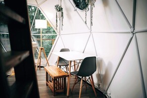 A tent with a table and chairs, a bench, and hanging plants.