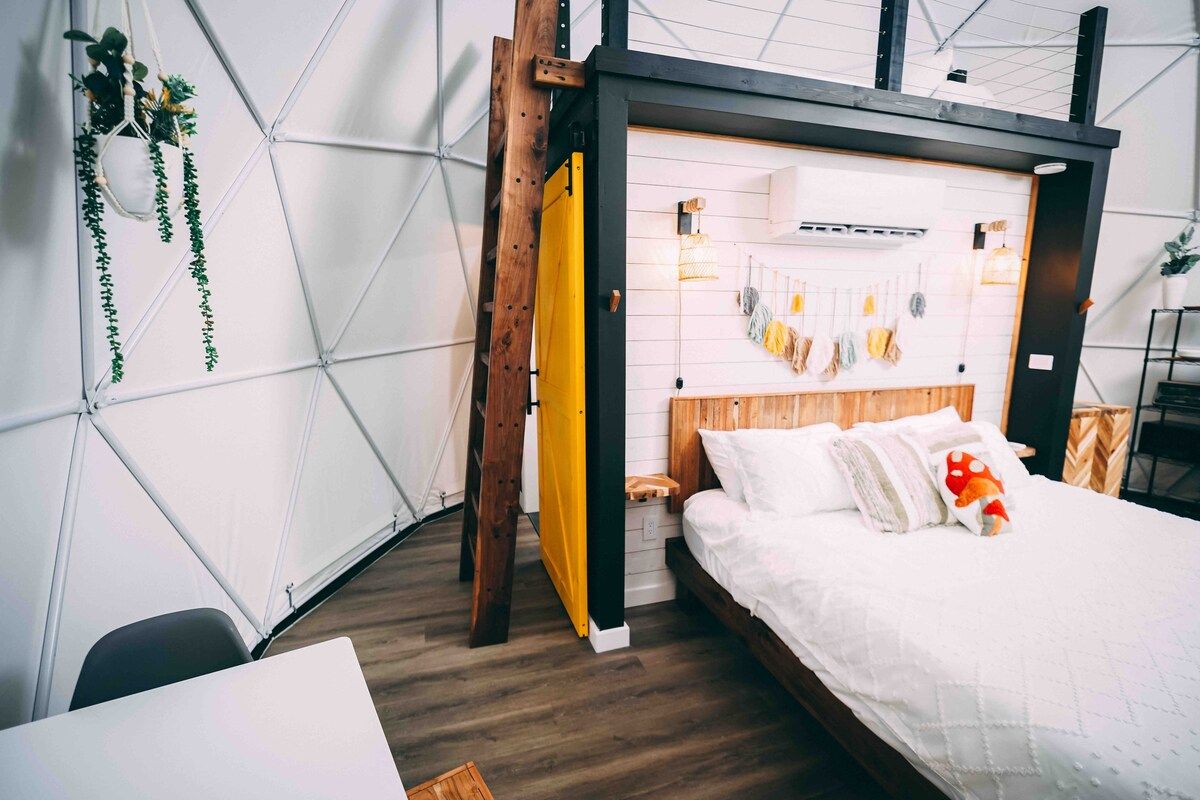 Une chambre à coucher moderne avec un lit, une tête de lit en bois et un motif géométrique sur le mur.