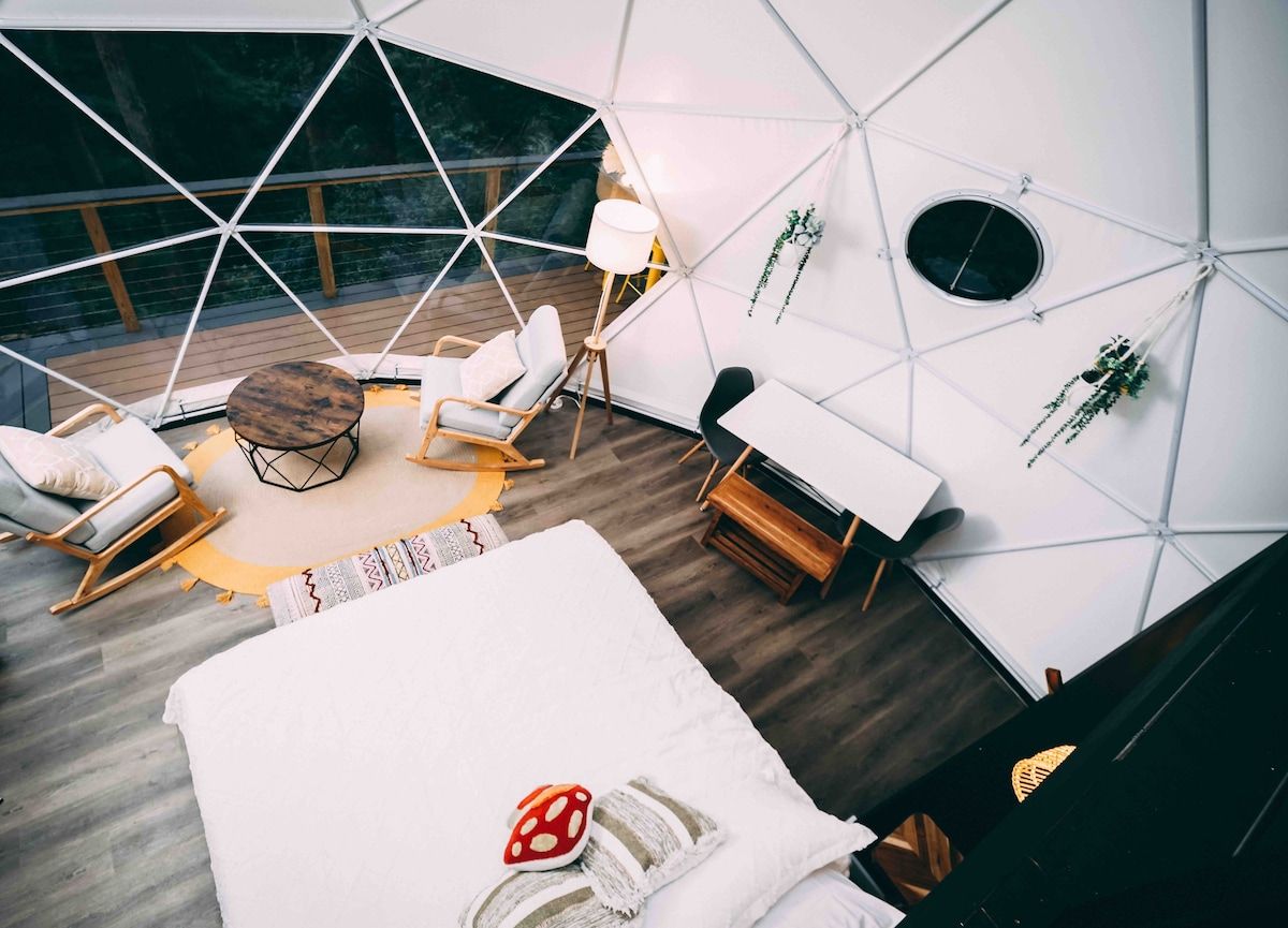 A modern, geometric interior with a bed, seating area, and a small table.