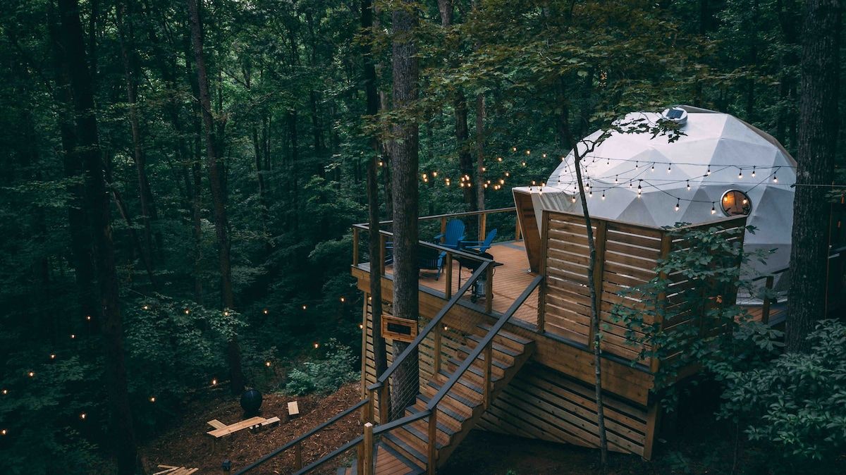 A treehouse with a wooden deck and a dome-shaped structure.
