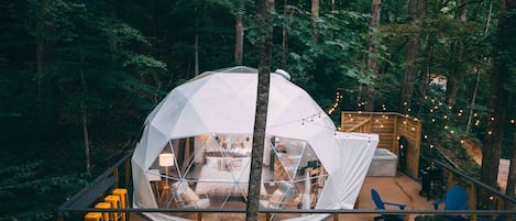A geodesic dome structure with a wooden deck and seating area.