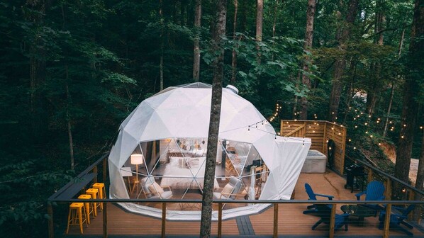 A geodesic dome structure with a wooden deck and seating area.