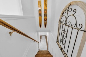 Un escalier avec une rampe en bois et une porte en métal au sommet.