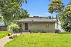 Une maison de plain-pied avec un porche à l’avant, un petit jardin devant et une cheminée bien visible.