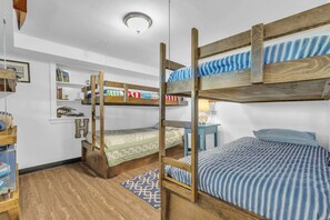 Une chambre avec un lit superposé, une échelle en bois, un petit bureau et une bibliothèque.