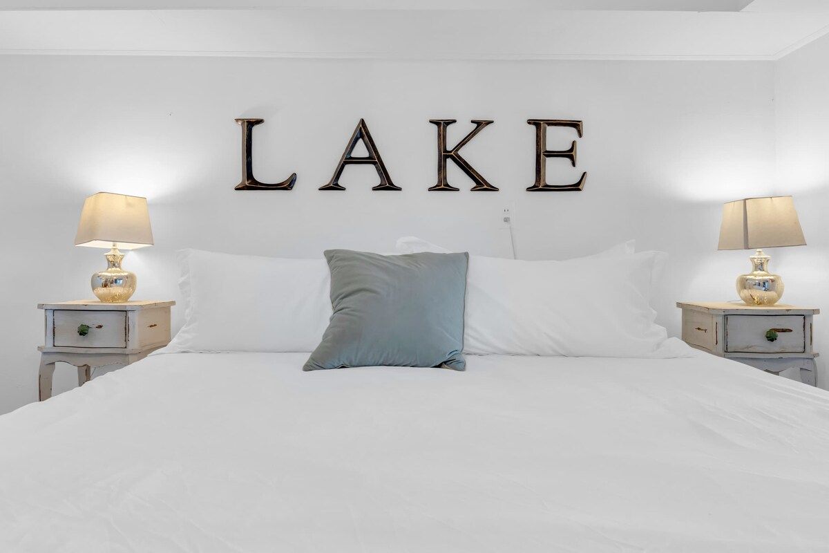 A bed with white bedding, a single blue pillow, and two bedside tables with lamps.