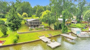 A lakeside property with a dock, a house with a covered patio, and a boat. - 3/2 Lake Front - Hot Tub - 2 King Beds - Sleeps 8 (Lyman)