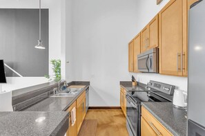 Une cuisine moderne dotée de plans de travail en granit, d’appareils électroménagers en acier inoxydable et d’armoires en bois.