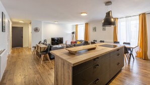 Un apartamento moderno con una zona de comedor de madera, una isla de cocina y un espacio de estar con sofá y televisor.