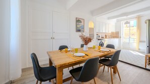 A dining area with a wooden table, black chairs, and a vase of dried flowers.