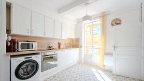 A compact kitchen with a washing machine, microwave, and oven.