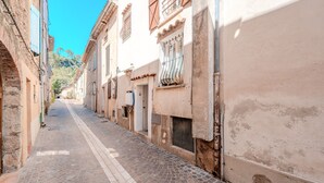 A narrow cobblestone street flanked by historic buildings with visible windows and doors.
