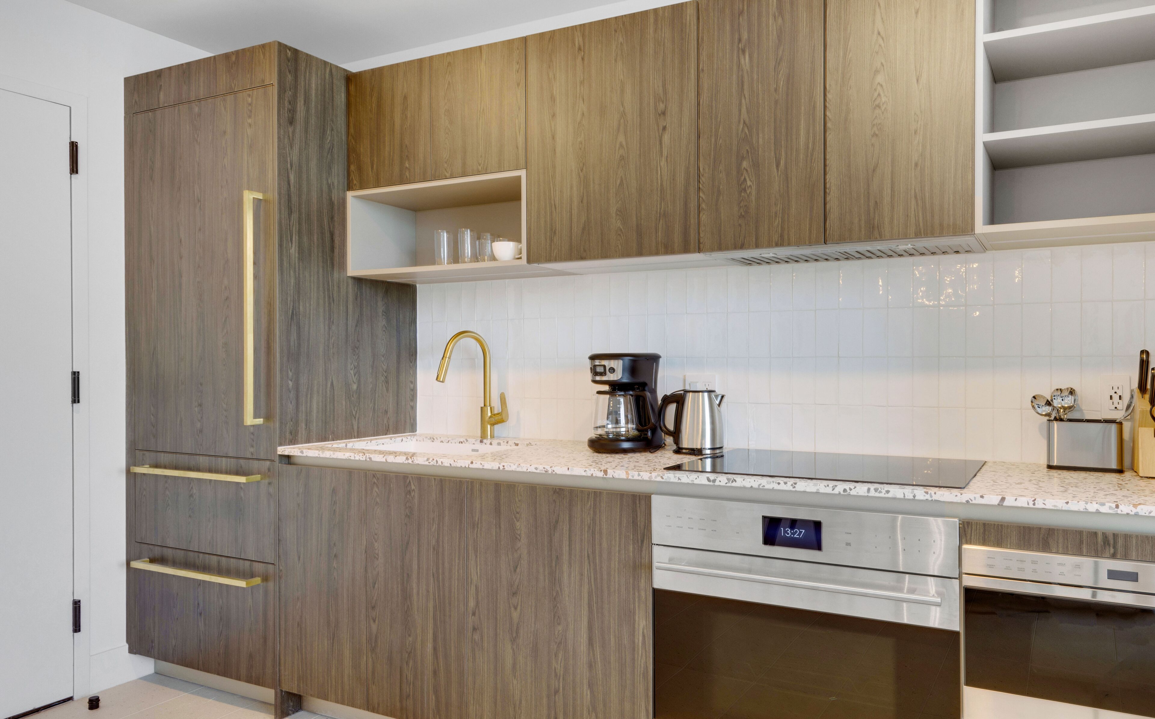 A modern kitchen with wooden cabinets, a stainless steel dishwasher, and a coffee maker.