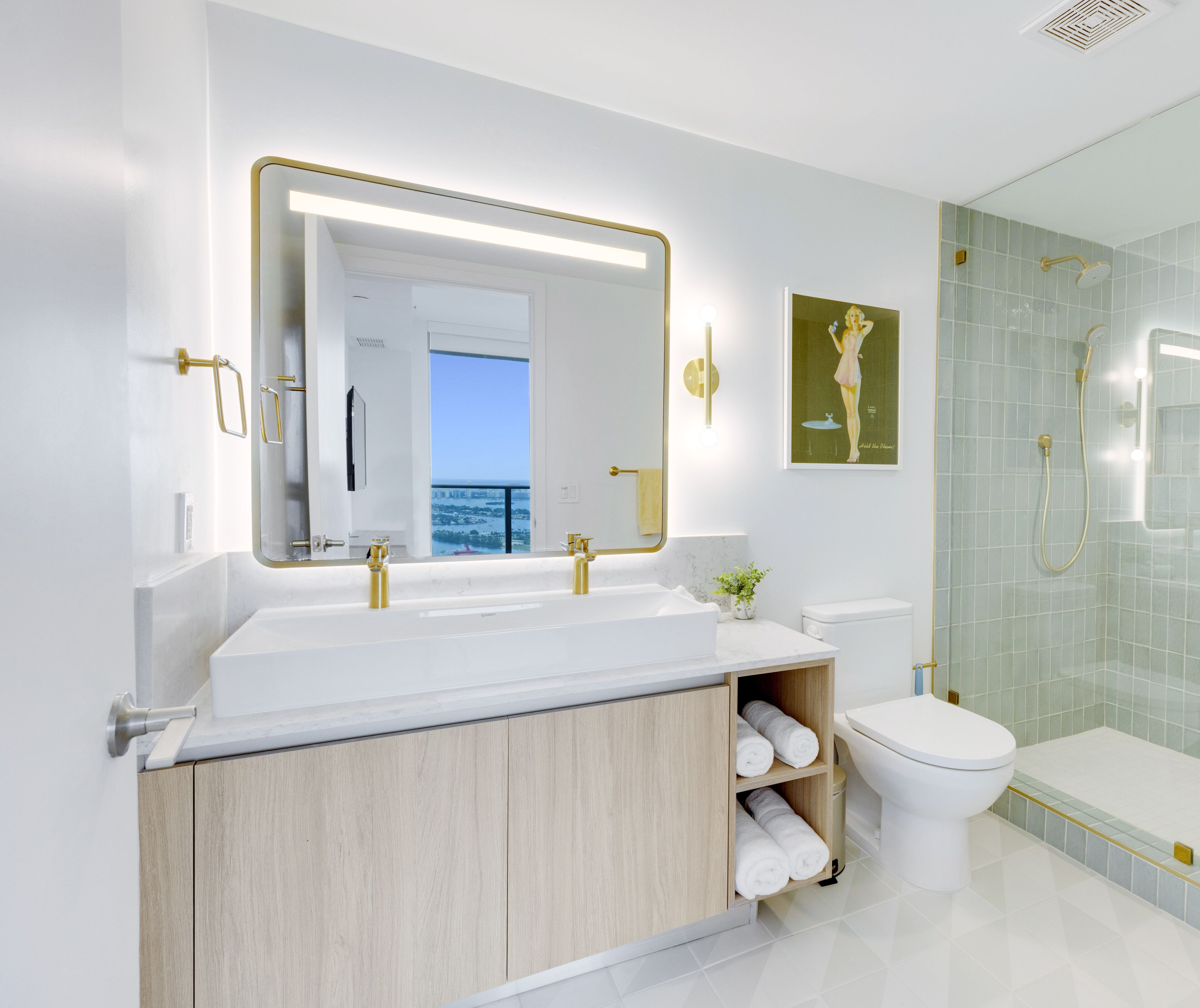 A modern bathroom with a large mirror, dual sinks, a toilet, and a glass-enclosed shower.