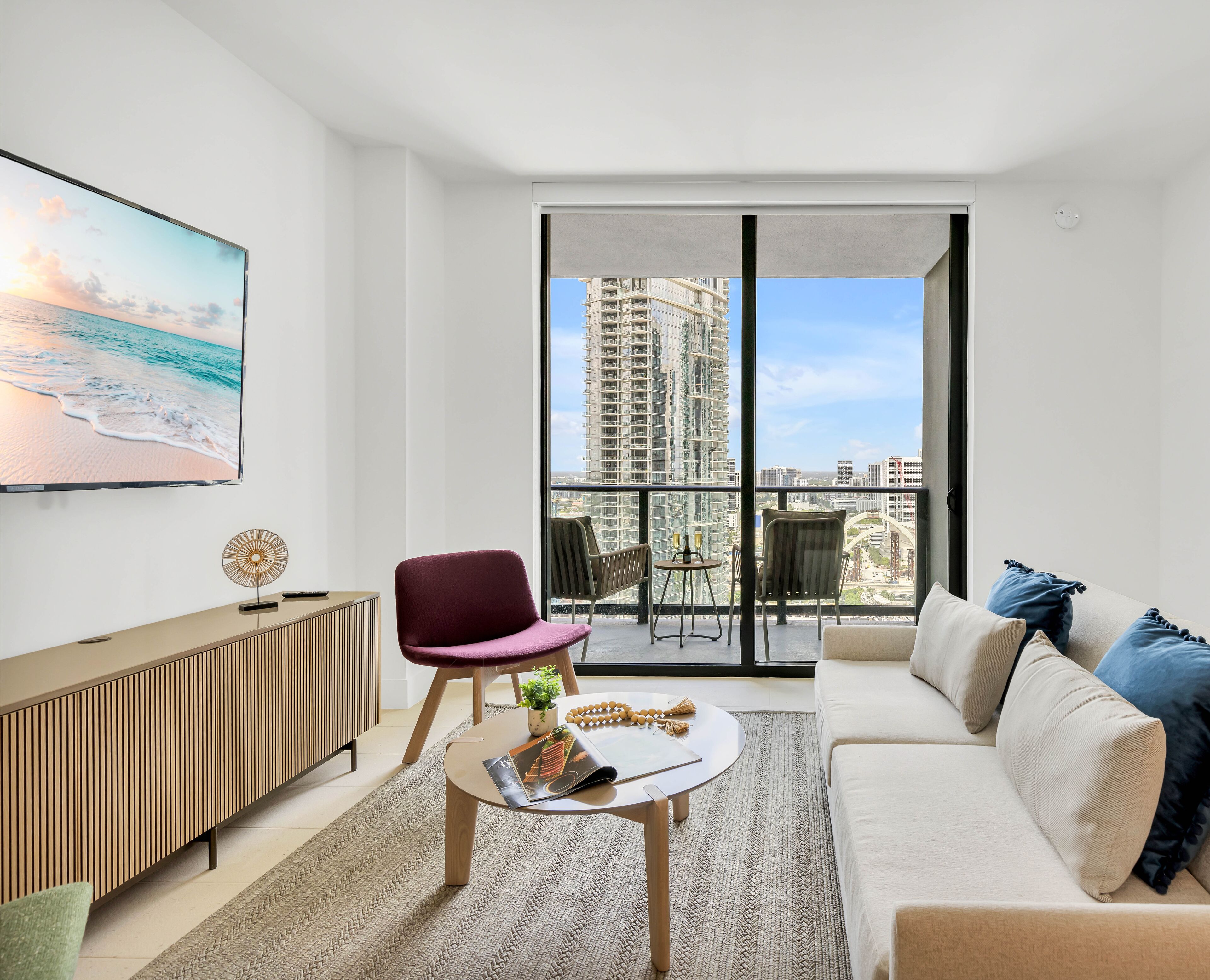 A modern living room with a large window, a sofa, a coffee table, and a TV.