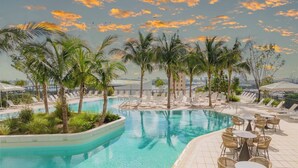 A pool area with lounge chairs and tables, surrounded by palm trees and a view of the city skyline. - Stay Sol Downtown (Miami)