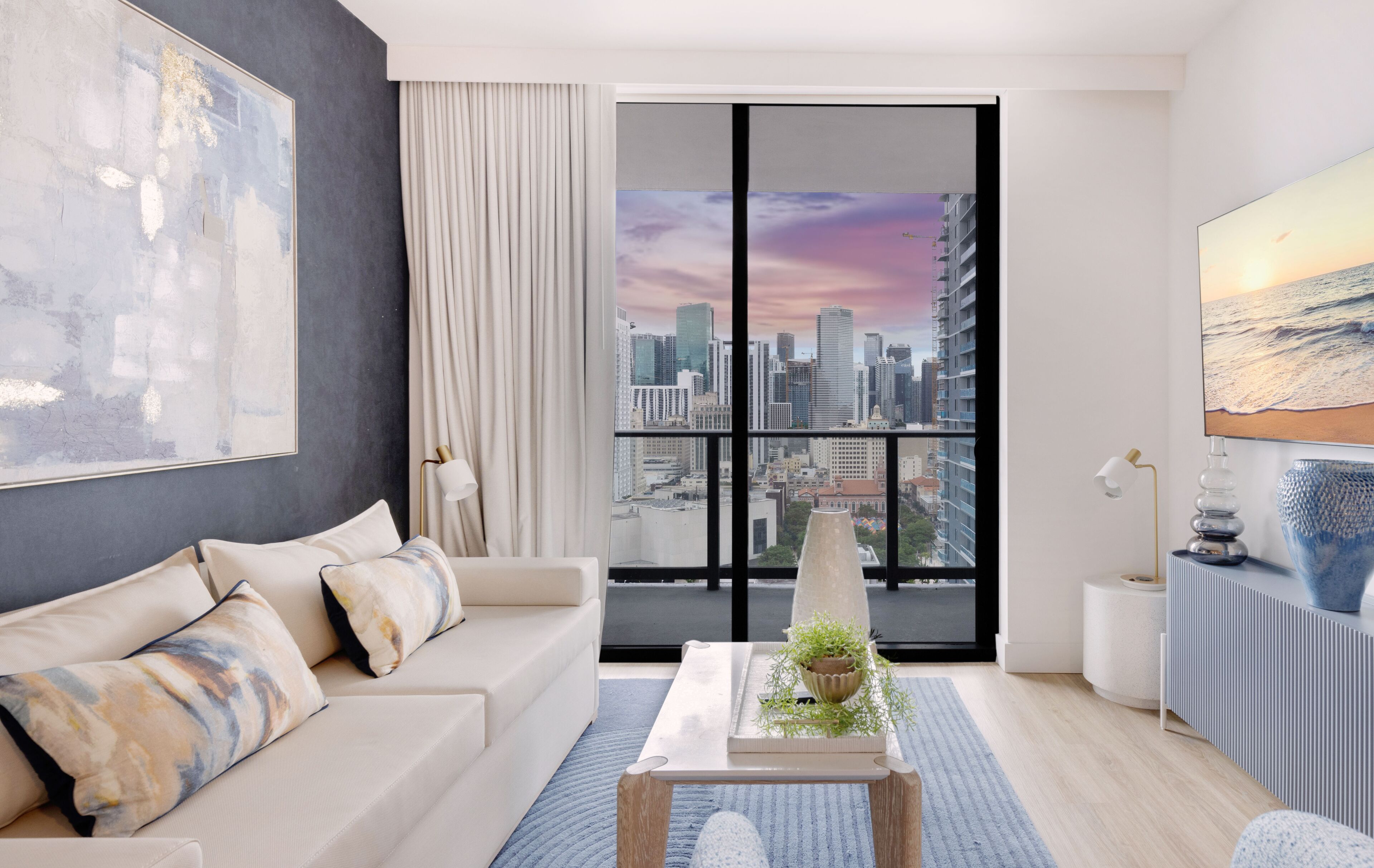 A modern living room with a large window, a sofa, a coffee table, and a city view.